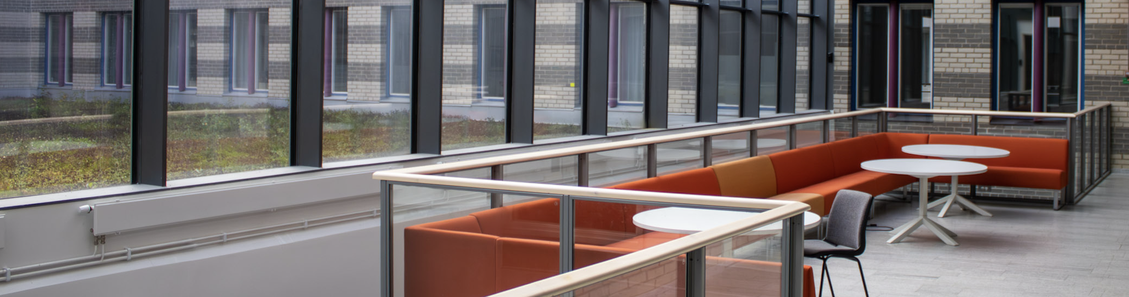 Red couches on a balcony infront of big windows.